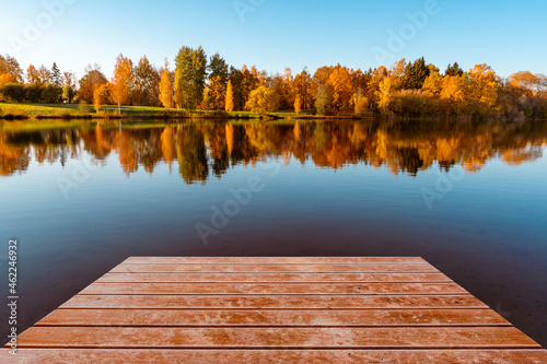 Wooden pier and colorful foliage reflections in lake water © graja