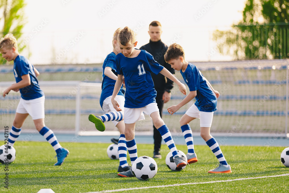 Group of Soccer Team Players on Training Session with Coach. Happy Kids Kicking Football Balls on Summer Training Camp