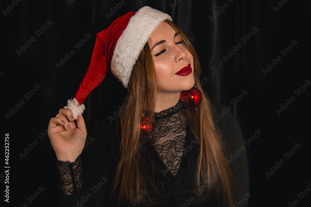 Beautiful blonde in a hat of Santa Claus. Making a wish to the chimes. New Year concept. Beautiful blonde in a hat of Santa Claus. Making a wish to the chimes. New Year concept.