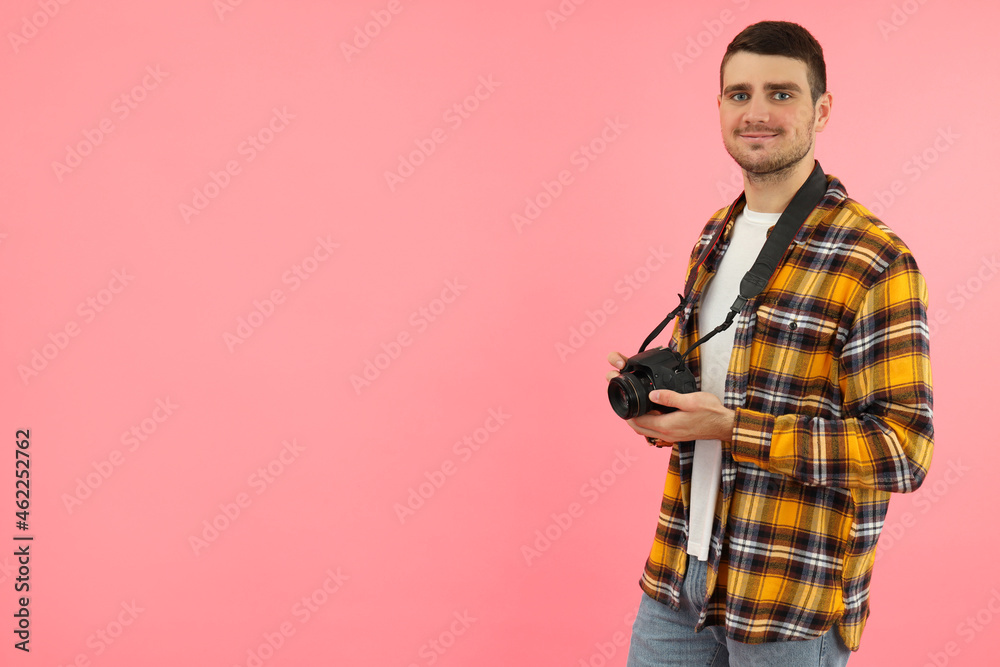 Young man with photo camera on pink background, space for text Young man with photo camera on pink background, space for text