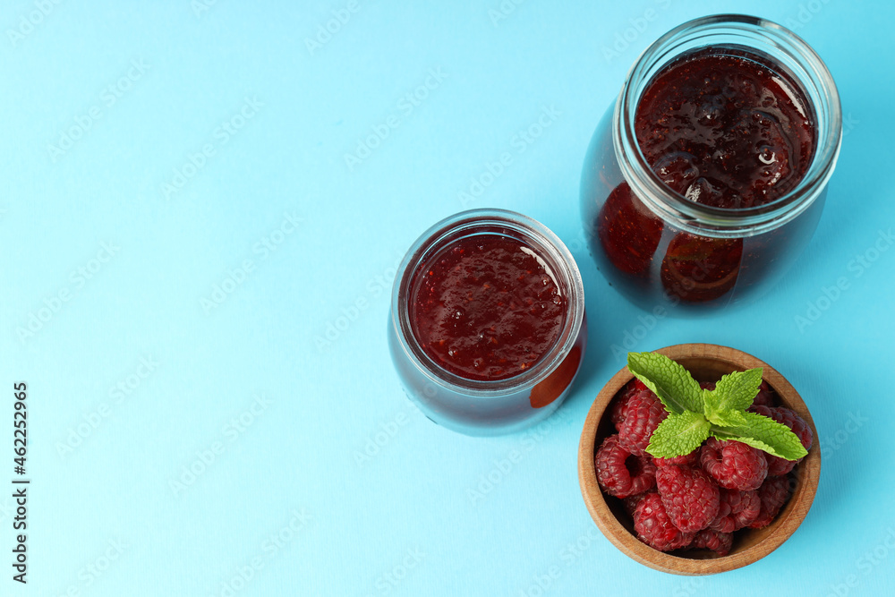 Jars of raspberry jam with ingredients on blue background Jars of raspberry jam with ingredients on blue background