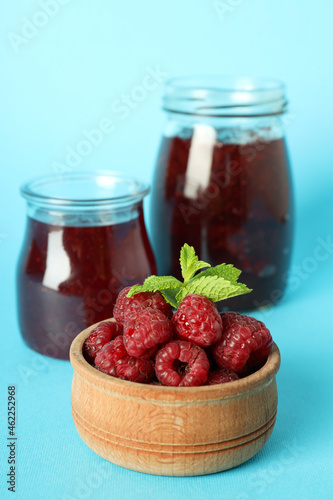 Jars of raspberry jam with ingredients on blue background
