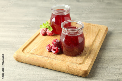 Glass jars of raspberry jam with ingredients on wooden board photo