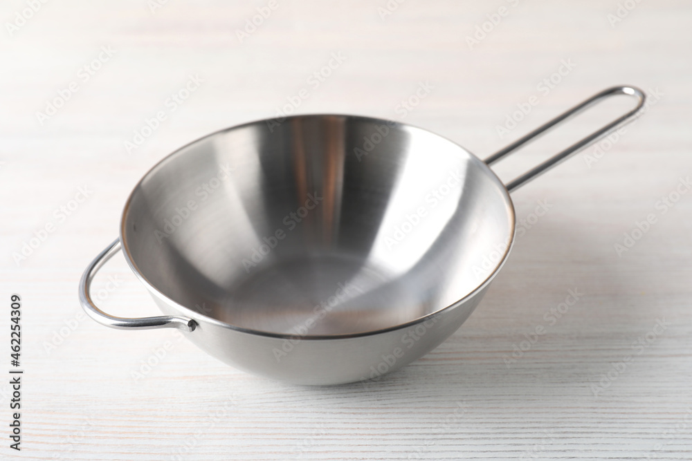 Metal bowl on white wooden background, close up Metal bowl on white wooden background, close up