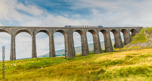 A view of a train crossing the Ribblehead Viaduct, Yorkshire, UK in summertime photo