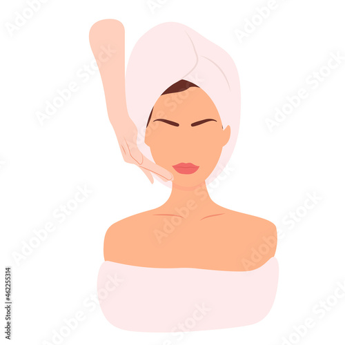 A woman in a towel makes a facial massage. Beauty procedures. Facial skin care.