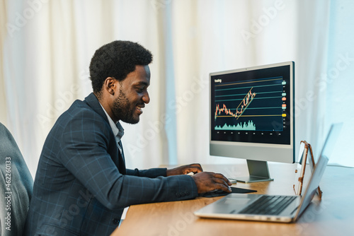 Black male broker using computer and trading online