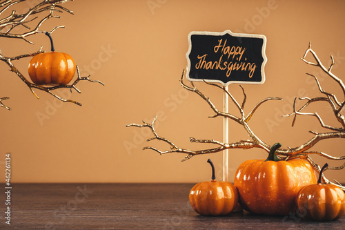 Happy Thanksgiving banner. Orange pumpkins on table with golden branches. happy banner party decoration. Halloween. copy space. brown background.