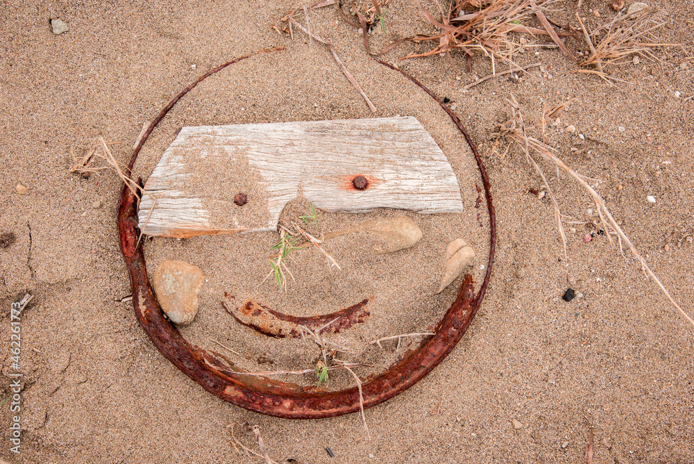 Smile sign in the middle of the beach in the contour of rusty iron with nails instead of eyes