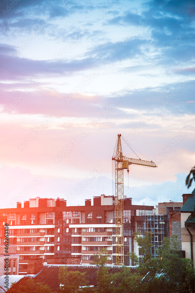 Construction crane on the background of the structure at sunrise (growth in demand for real estate - concept)