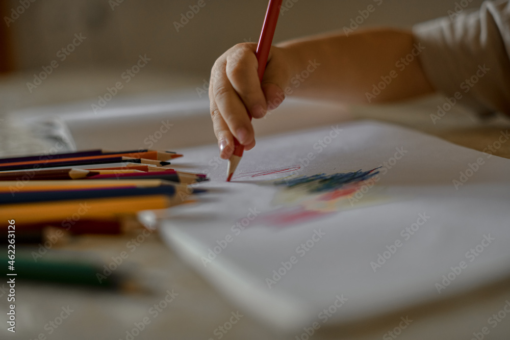 A little boy of three years draws a drawing with colored pencils