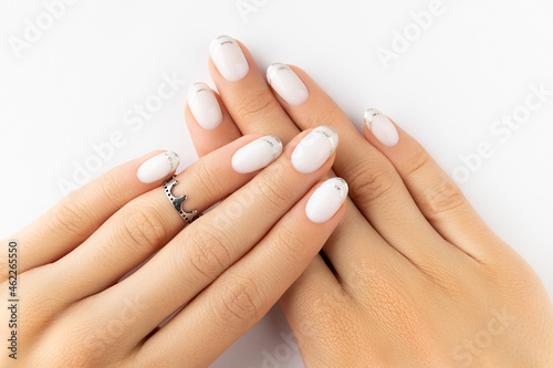 Beautiful groomed womans hands with modern french nail design on white