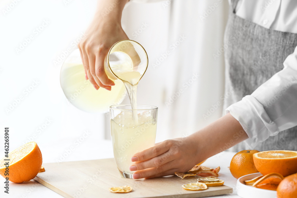 Woman making fresh citrus juice at table in kitchen Woman making fresh citrus juice at table in kitchen