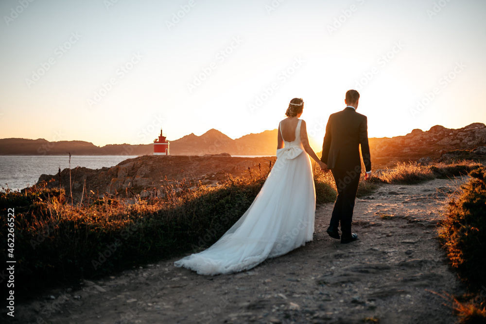 Just married couple walking towards a lighthouse