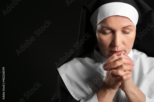 Mature nun praying on dark ...