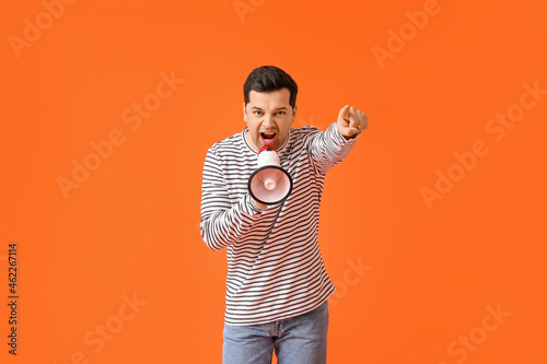 Protesting young man with megaphone on color background