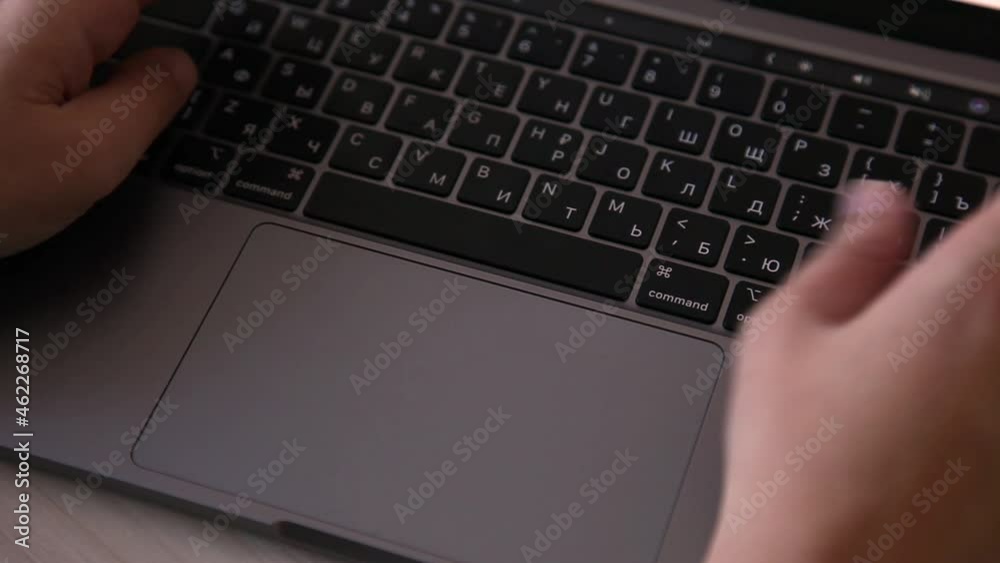 Female hands are typing text on the keyboard of a gray laptop Female hands are typing text on the keyboard of a gray laptop