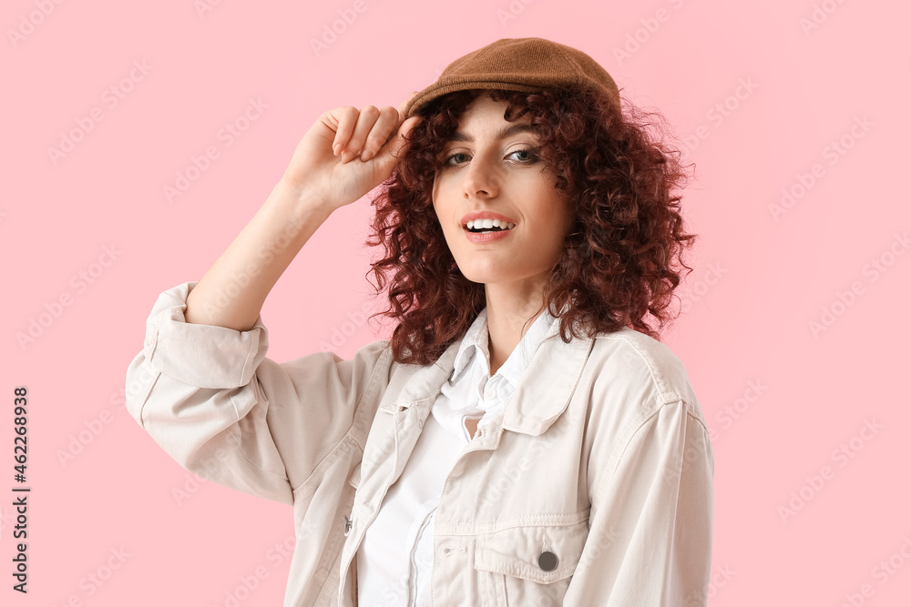 Smiling woman adjusting flat cap on pink background Smiling woman adjusting flat cap on pink background