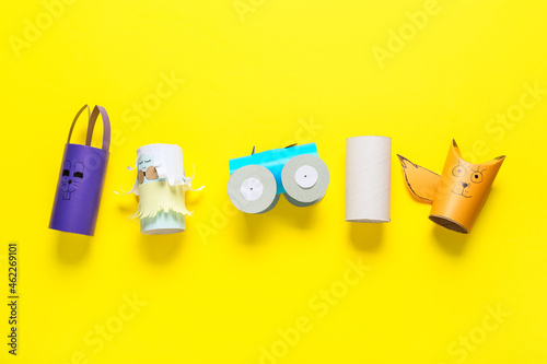 Different figures made of cardboard tubes for toilet paper on yellow background
