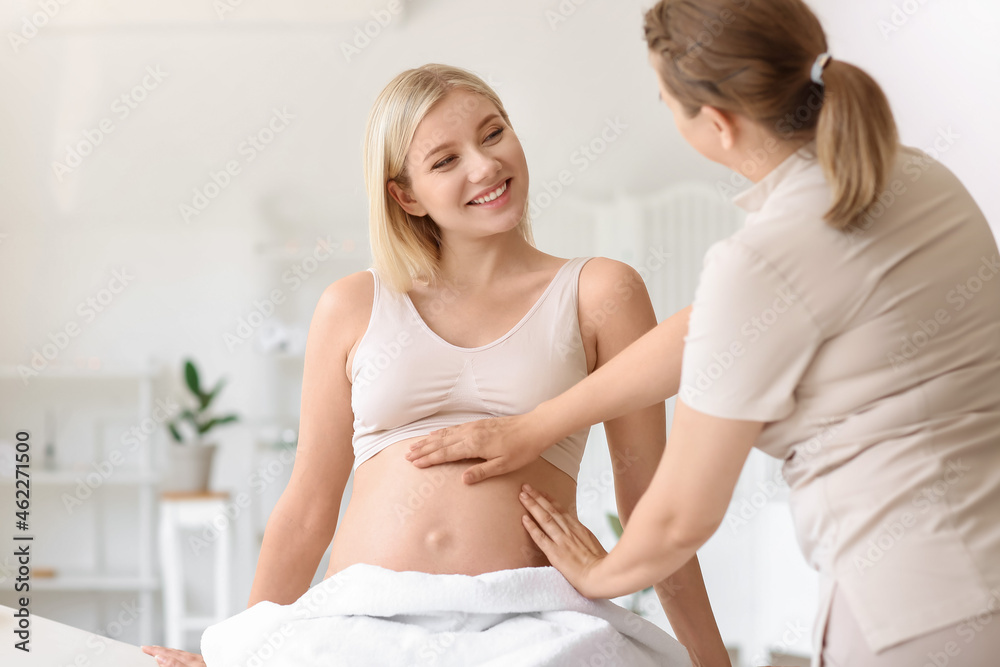 Young pregnant woman having massage in spa salon