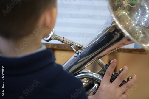 Boy child playing a musical instrument silver trumpet background music