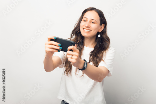 Playful young woman is playing at the phone she is holding.