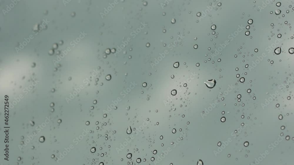 Raindrops on the glass of the car. Driving in the rain, cloudy sky and splashing water on the window. selective focus, shallow depth of field Raindrops on the glass of the car. Driving in the rain, cloudy sky and splashing water on the window. selective focus, shallow depth of field