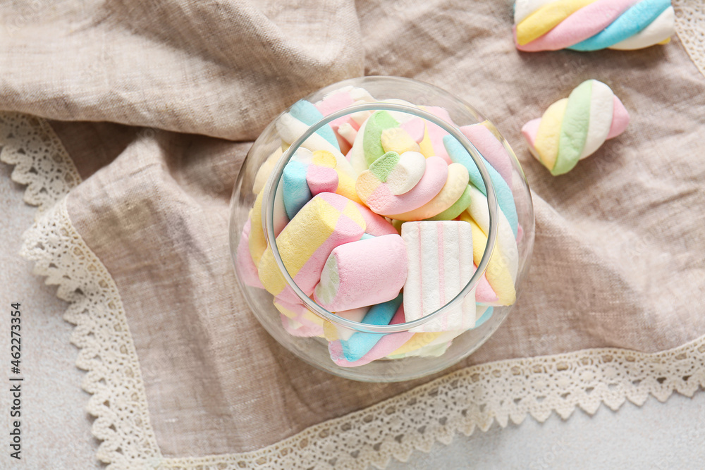 Glass with sweet marshmallows on light background