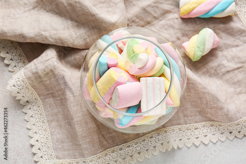 Glass with sweet marshmallows on light background