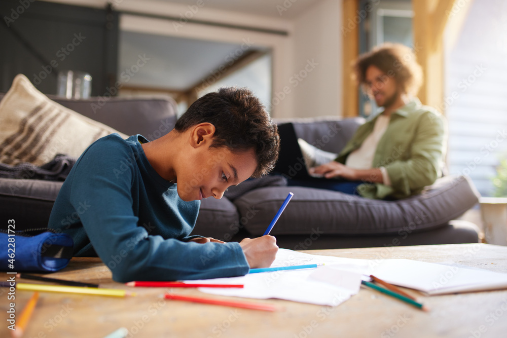 Fototapeta premium Boy drawing on paper on coffee table at home