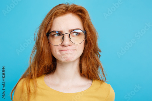 Close up Portrait young beautiful attractive redhair girl with eyeglass worry with something. Blue Pastel Background. Copy space. photo