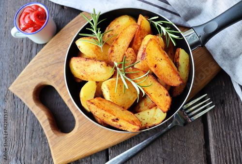 Konstfotografi Fried potatoes with rosemary in iron pan