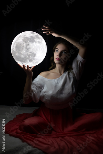beautiful girl with a moon in her hands on a black background