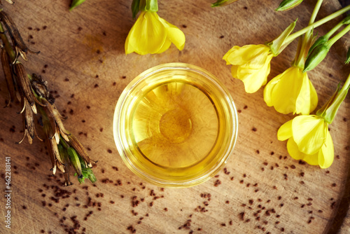 A bowl of evening primrose oil with evening primrose seeds and flowers
