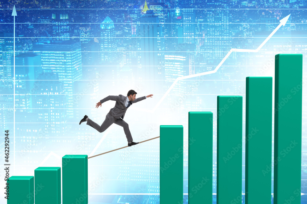 Businessman walking on tight rope between bar chart Businessman walking on tight rope between bar chart