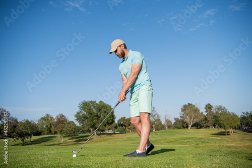busy golfer in cap with golf club, golf course
