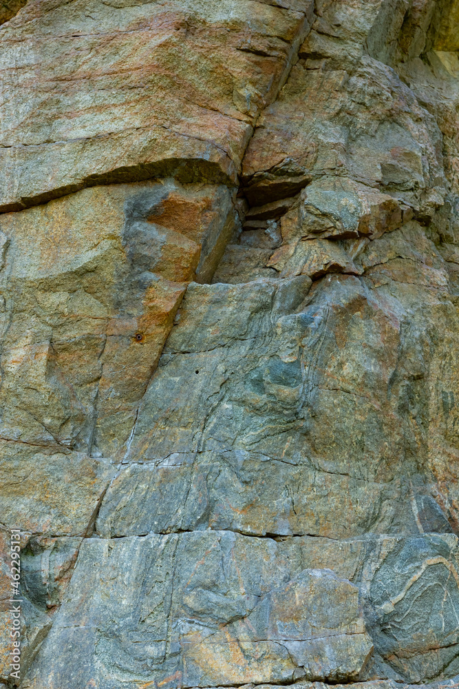 Naklejka premium Granite rocks in sunlight. Large sheer granite rock. Hard rock on a sunny day