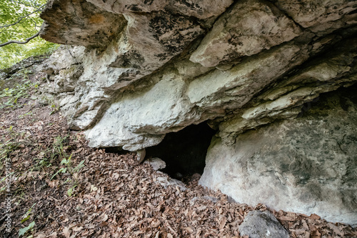 The entrance to a small cave in a white karst rock. The concept of geology and Cretaceous limestone