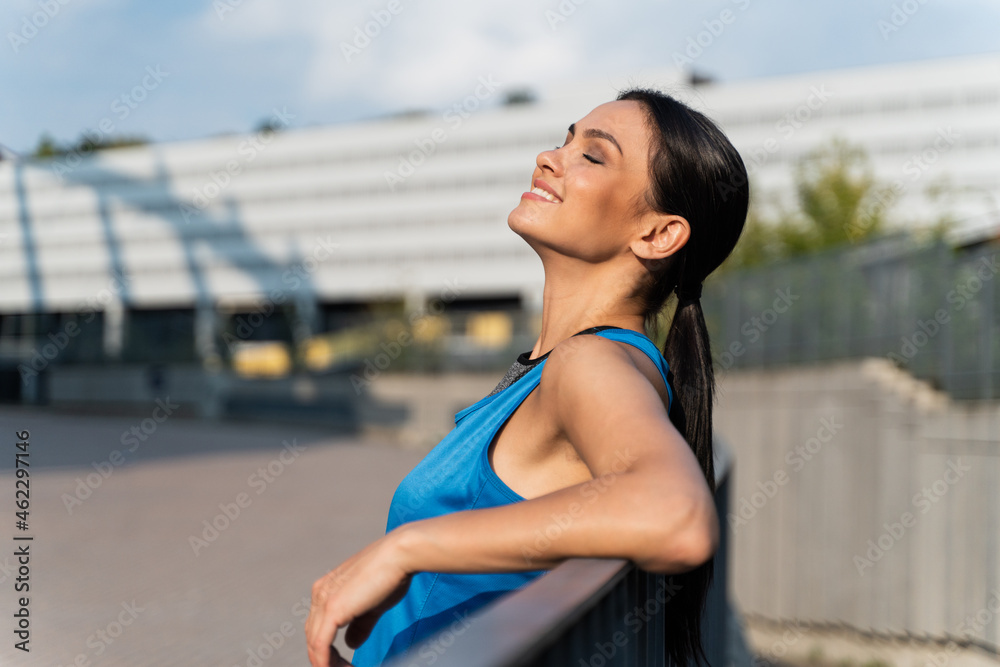 Moment of pleasures. Waist up portrait view of the brunette healthy girl closed her eyes with pleasures while resting at the street after workout. Sport concept Moment of pleasures. Waist up portrait view of the brunette healthy girl closed her eyes with pleasures while resting at the street after workout. Sport concept