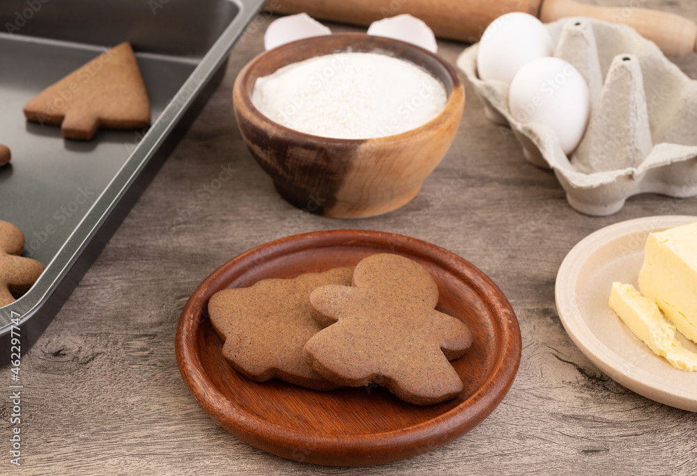 Traditional christmas gingerbread cookies over a wooden table with ingredients Traditional christmas gingerbread cookies over a wooden table with ingredients