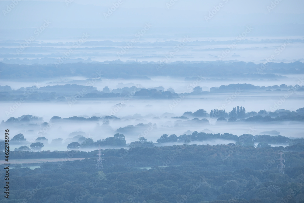 Beautiful foggy morning landscape image looking across fields on the South Downs National Park in rolling English contryside during late Summer Beautiful foggy morning landscape image looking across fields on the South Downs National Park in rolling English contryside during late Summer