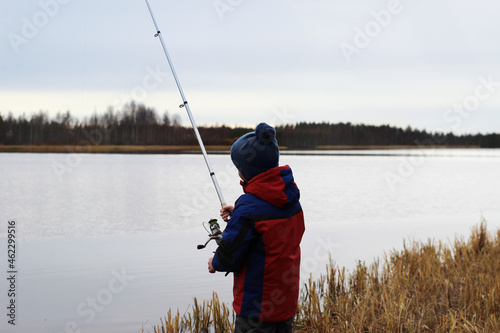 little boy fishing in autumn on the lake