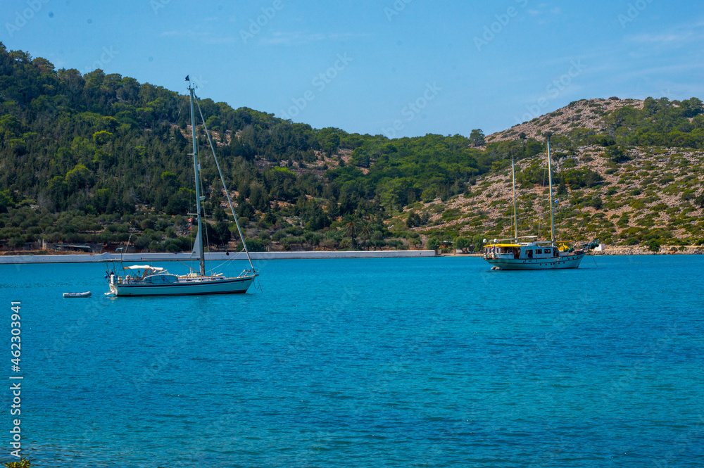 Two white boats sailing close to the coast blue aegean sea in Greece Two white boats sailing close to the coast blue aegean sea in Greece