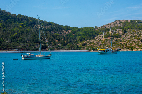 Two white boats sailing close to the coast blue aegean sea in Greece