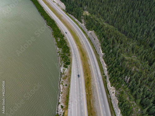 Aerial shot of a two-lane road surrounded by forests and water in the daylight photo