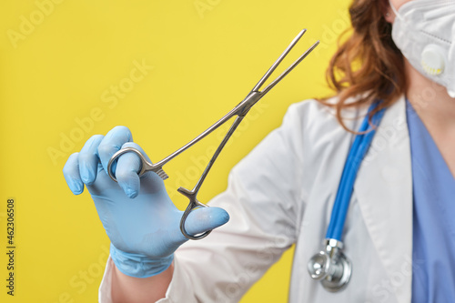 The doctor holds a surgical clamp in his hand. Nurse with a medical clip with scissors in her hand, studio background photo