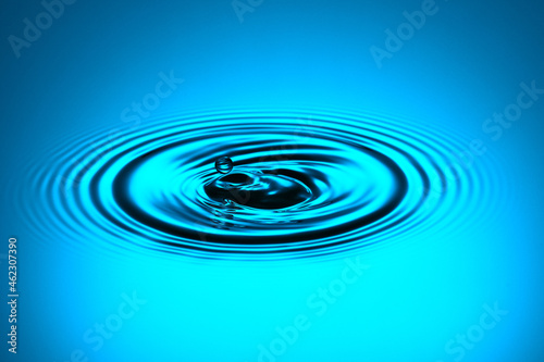 Water drop bouncing from the water surface and creating ripples.