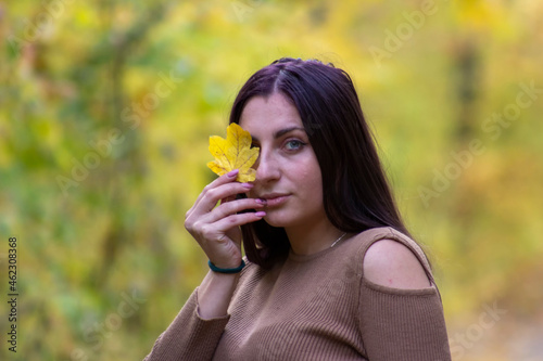 beautiful girl with a yellow leaf near the face