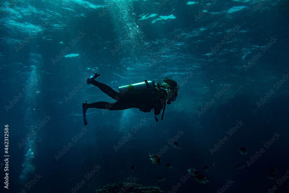 Woman scuba diver swimming in deep blue