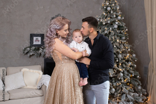 family with little baby boy enjoying their time together at home near Christmas tree